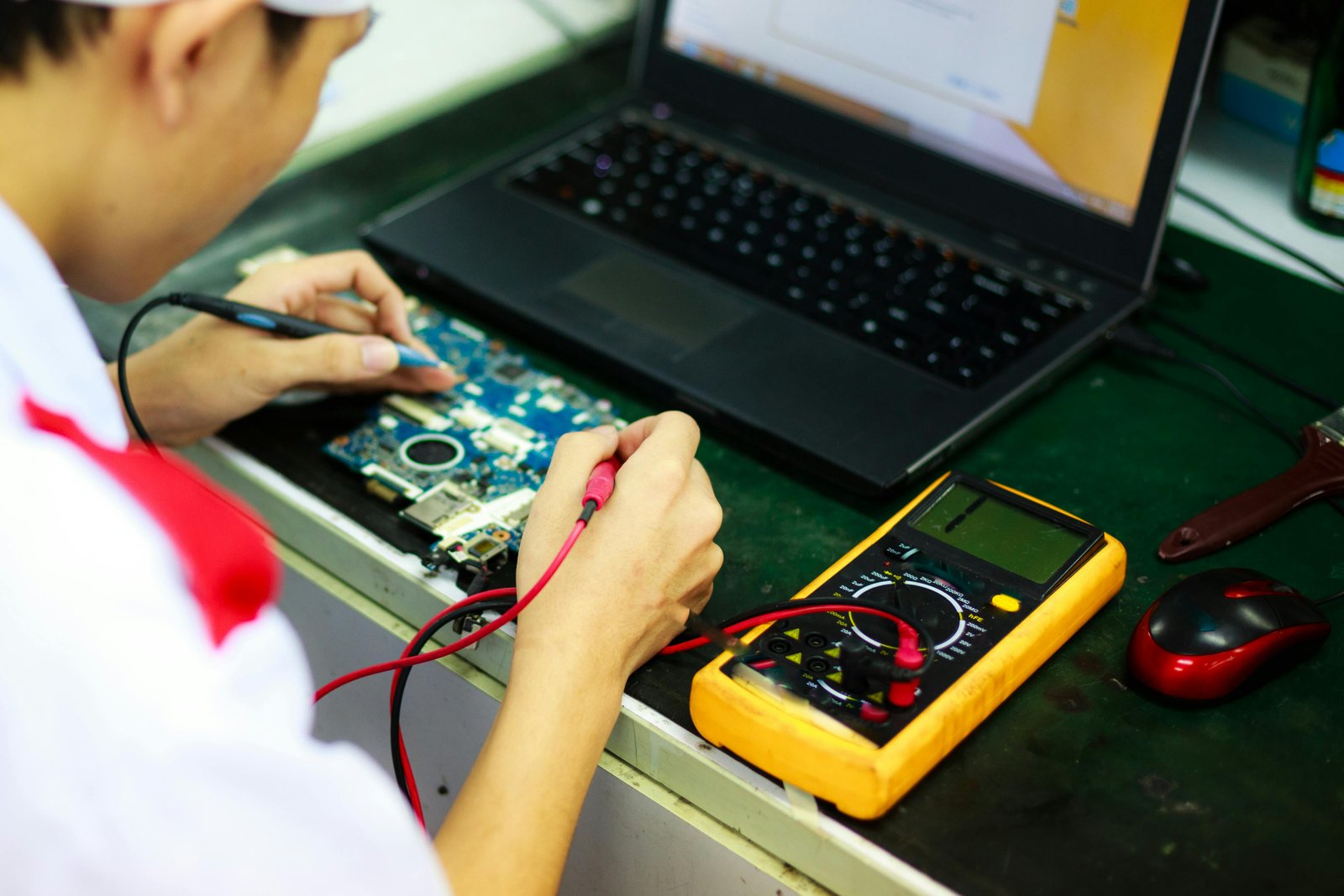 Technician testing laptop hardware with a multimeter during computer diagnostics